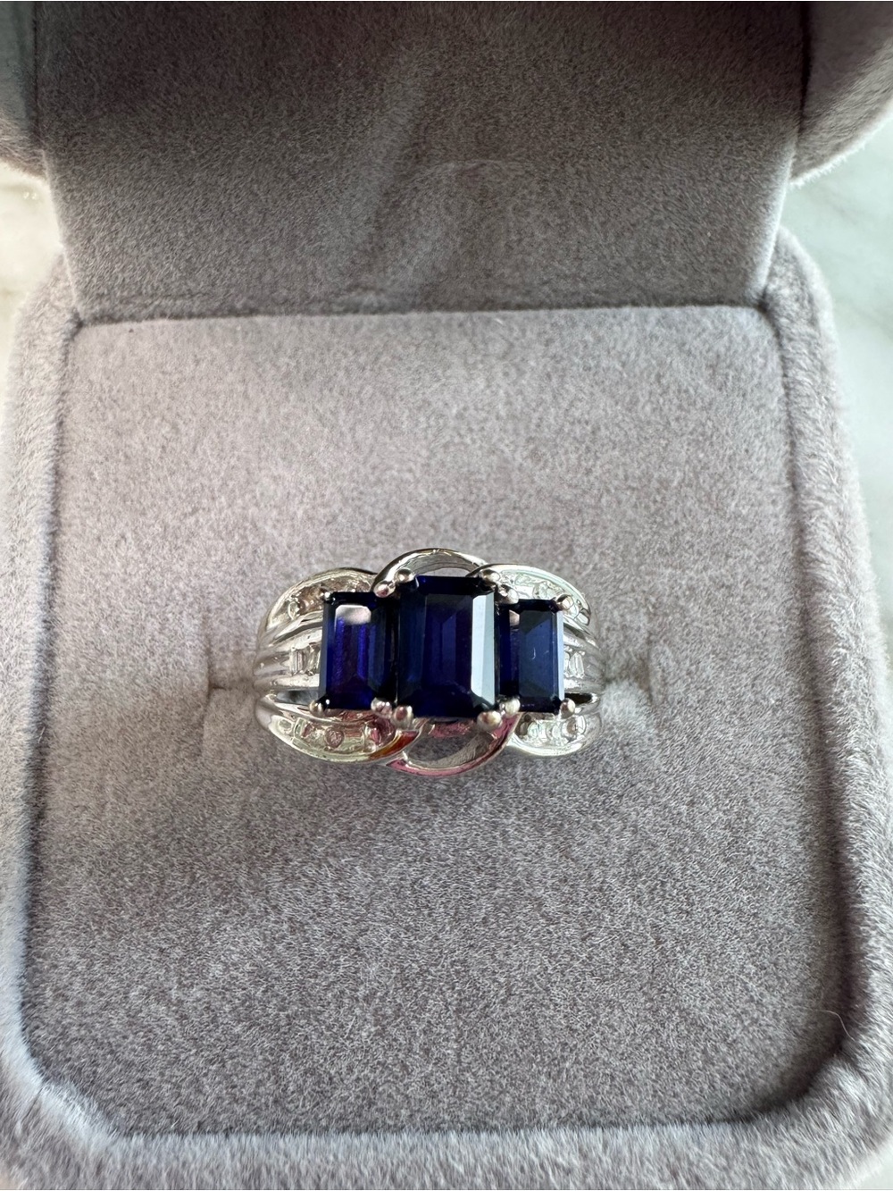 10K white gold ring with emerald cut blue sapphire and diamond accents